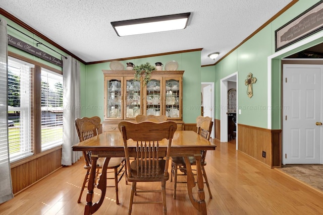 dining space with a textured ceiling, crown molding, vaulted ceiling, and light wood-type flooring