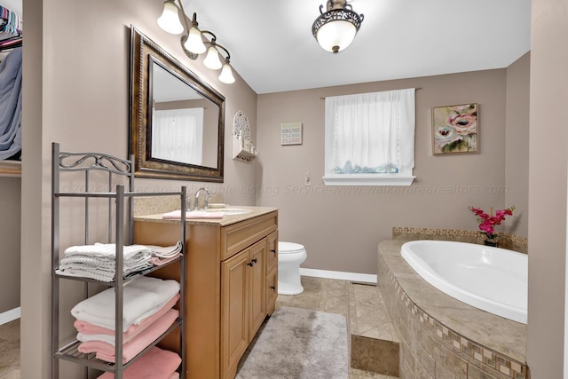 bathroom with tile patterned flooring, vanity, toilet, and tiled bath