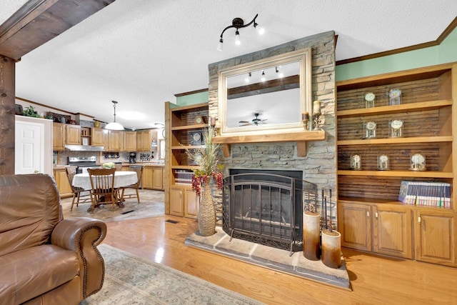 living room featuring a textured ceiling, crown molding, a fireplace, light hardwood / wood-style floors, and lofted ceiling