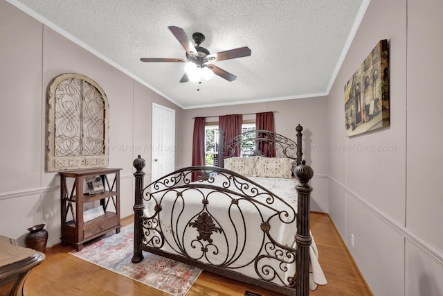 bedroom with ceiling fan, crown molding, wood-type flooring, and a textured ceiling