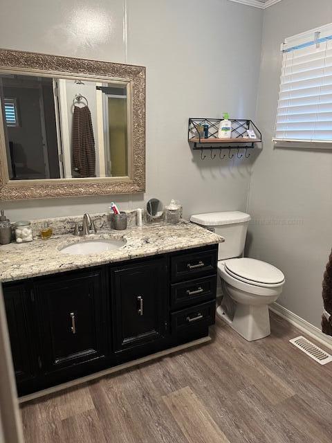 bathroom featuring toilet, vanity, ornamental molding, and hardwood / wood-style flooring