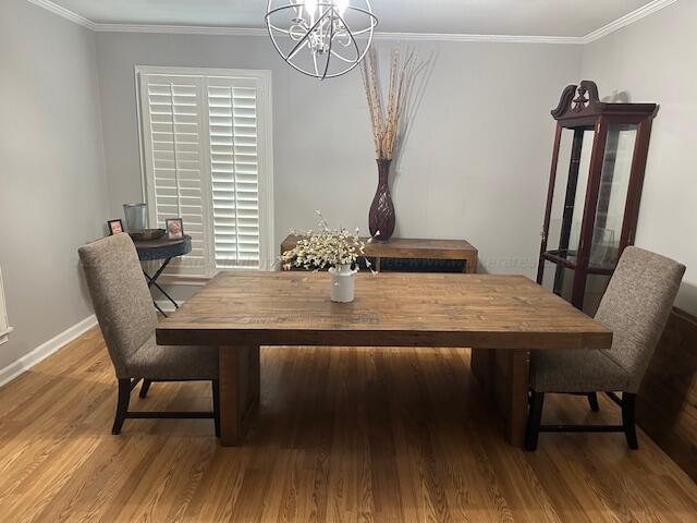 dining area with crown molding, a notable chandelier, and hardwood / wood-style flooring