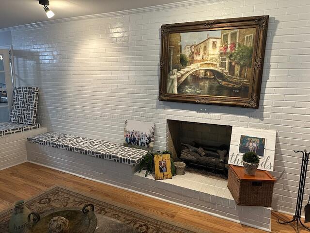 sitting room featuring a fireplace, ornamental molding, and hardwood / wood-style flooring