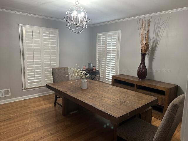 dining space featuring hardwood / wood-style flooring, a notable chandelier, and ornamental molding