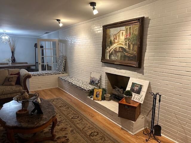 living area with hardwood / wood-style floors and brick wall