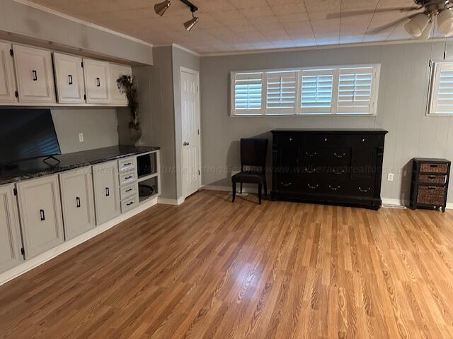 kitchen with crown molding, ceiling fan, dark stone countertops, light wood-type flooring, and white cabinetry