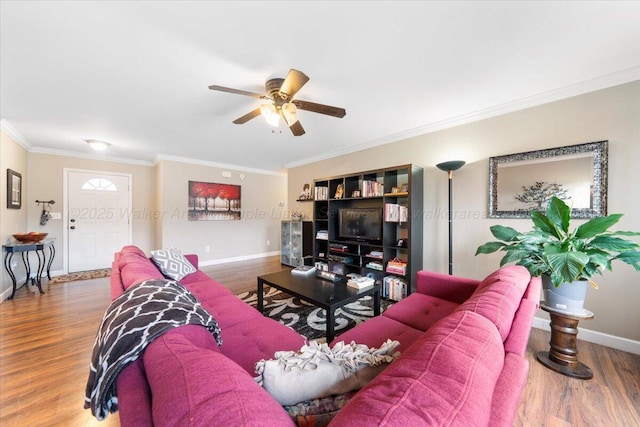 living area with ornamental molding, wood finished floors, a ceiling fan, and baseboards