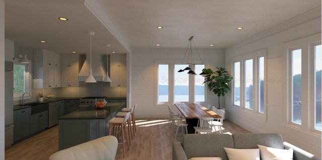 kitchen with dark countertops, a center island, wall chimney range hood, and wood finished floors