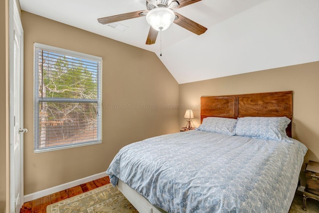 bedroom with dark wood-type flooring, vaulted ceiling, and ceiling fan