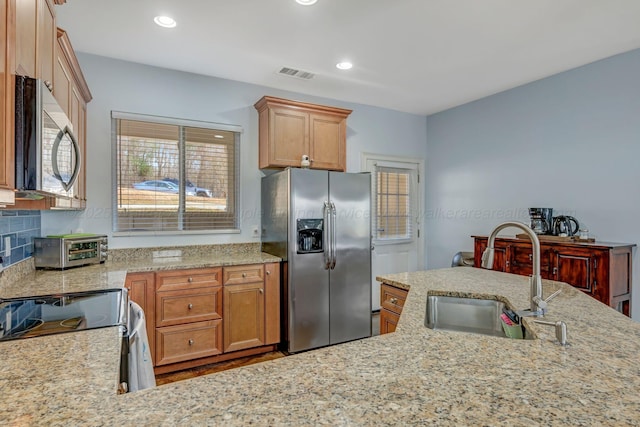 kitchen featuring light stone counters, sink, backsplash, and stainless steel appliances