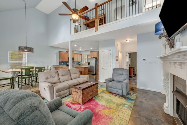 living room with ceiling fan, a fireplace, and a towering ceiling