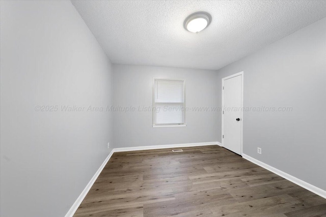 spare room with dark wood-type flooring and a textured ceiling