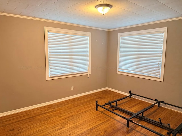 workout room featuring baseboards, wood finished floors, and crown molding