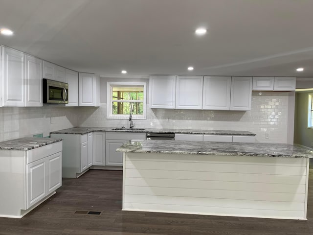 kitchen featuring white cabinets, sink, light stone counters, tasteful backsplash, and dark hardwood / wood-style flooring