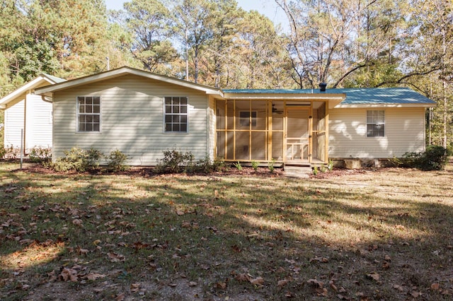 back of property with a lawn and a sunroom