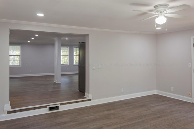 empty room with a wealth of natural light, dark wood-type flooring, and ornamental molding