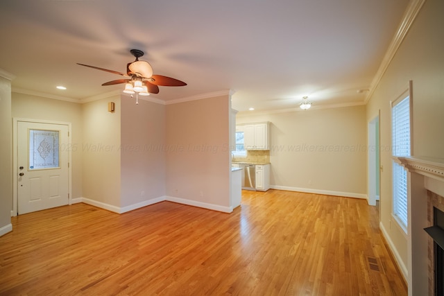 unfurnished living room featuring crown molding, ceiling fan, a fireplace, and light hardwood / wood-style flooring