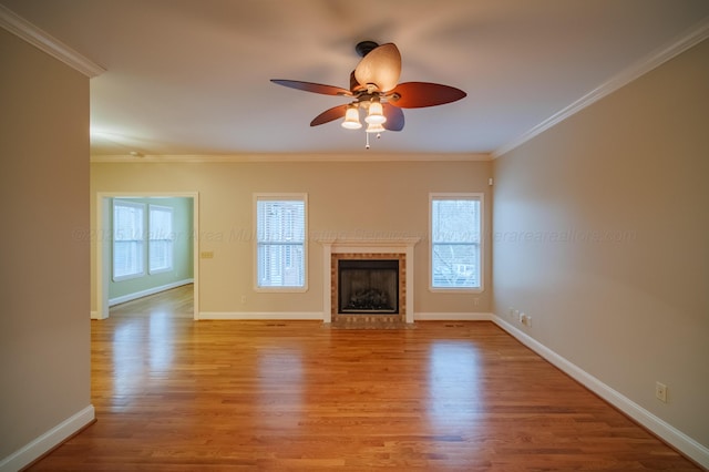 unfurnished living room featuring a tile fireplace, ornamental molding, ceiling fan, and light wood-type flooring