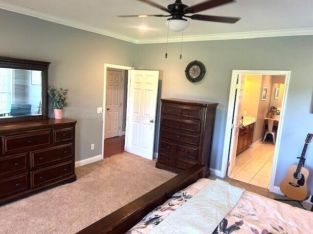 bedroom with light carpet, connected bathroom, ceiling fan, and crown molding