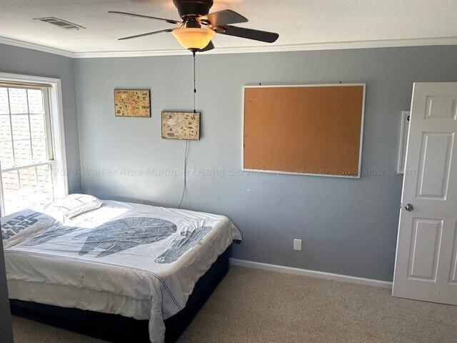 carpeted bedroom with ceiling fan and ornamental molding