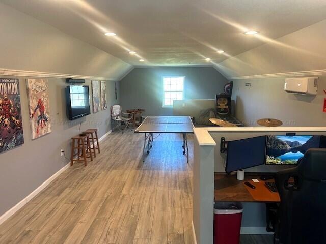 interior space featuring an AC wall unit, hardwood / wood-style floors, and vaulted ceiling