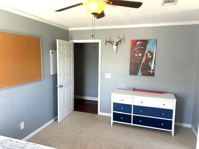 unfurnished bedroom featuring ceiling fan, light colored carpet, and crown molding