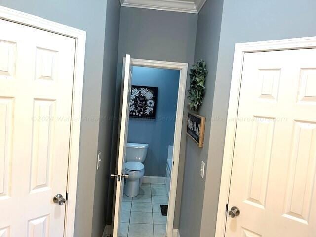 bathroom featuring tile patterned flooring, toilet, and crown molding