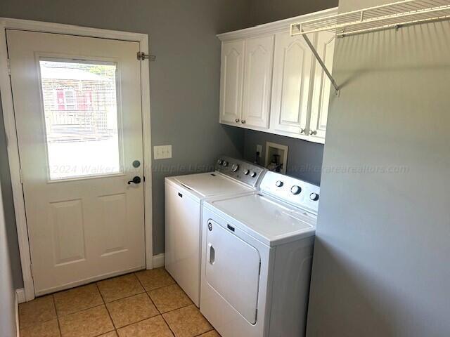 laundry area featuring cabinets, light tile patterned floors, and washer and dryer