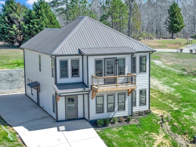 view of front of home with a balcony and a front lawn