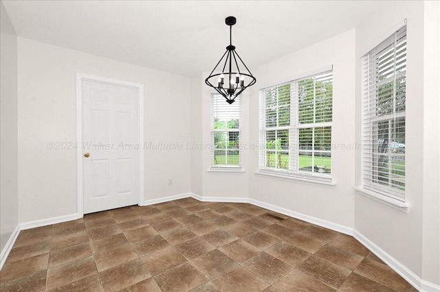 empty room featuring a chandelier and a wealth of natural light