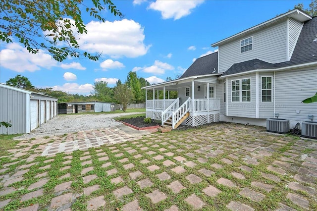 rear view of house with a porch, a garage, an outdoor structure, and central AC