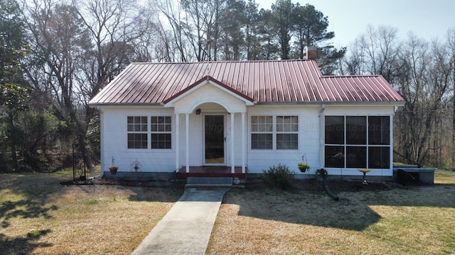 bungalow-style house with a chimney, a front lawn, and metal roof