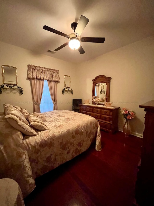 bedroom featuring a ceiling fan, visible vents, and wood finished floors