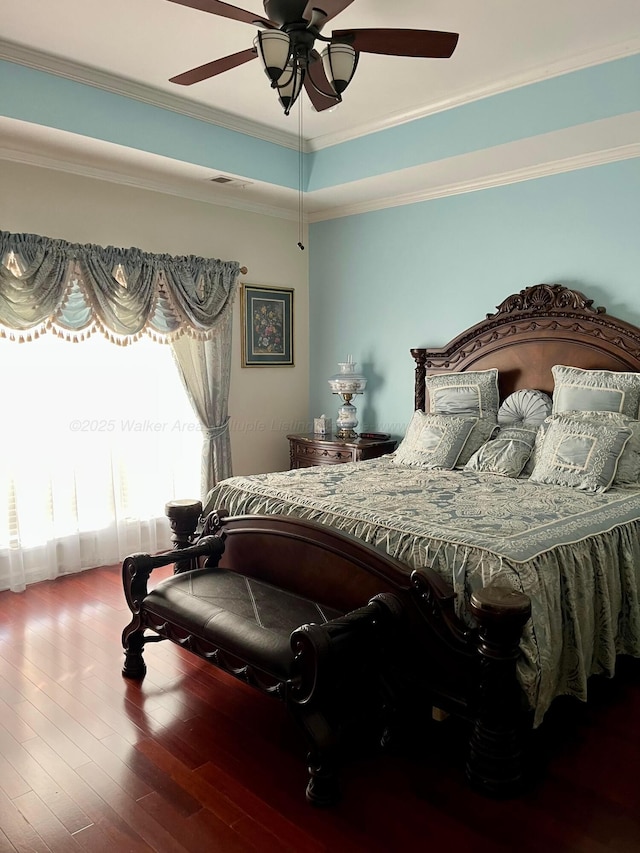 bedroom with crown molding, a tray ceiling, ceiling fan, and wood finished floors