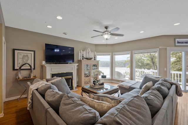 living room featuring wood-type flooring, a textured ceiling, and ceiling fan