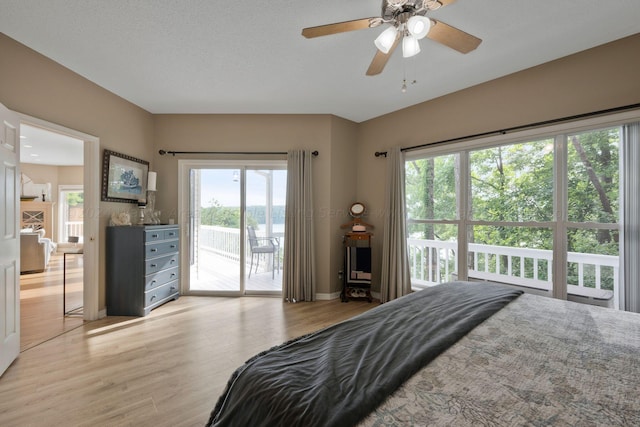 bedroom featuring access to exterior, ceiling fan, light hardwood / wood-style flooring, and a textured ceiling