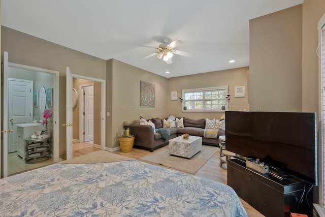 bedroom with ensuite bathroom, light hardwood / wood-style flooring, and ceiling fan