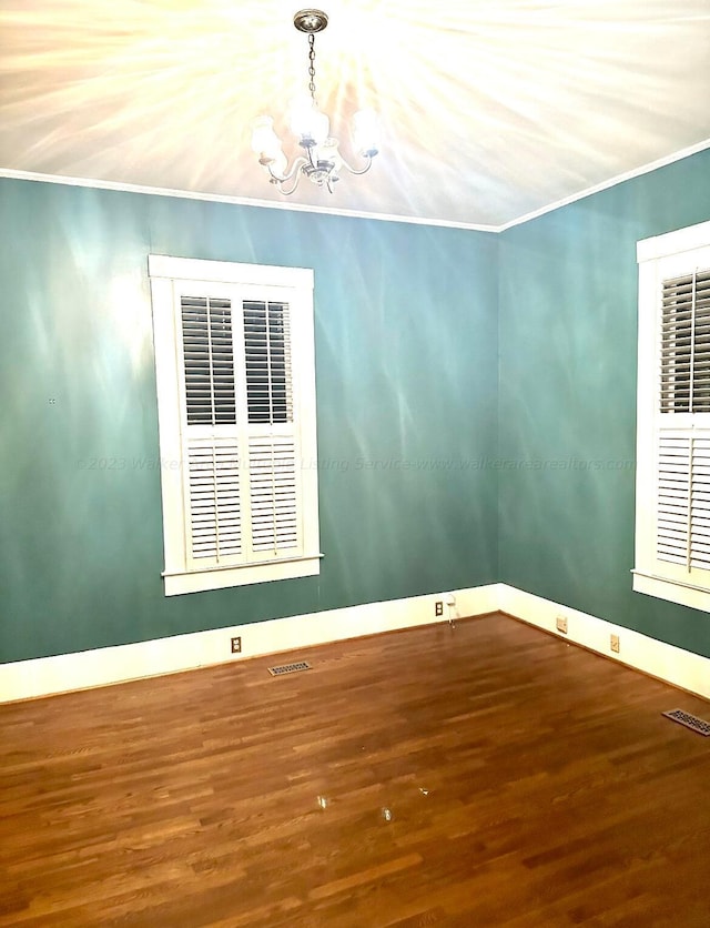 spare room featuring crown molding, a notable chandelier, and hardwood / wood-style flooring