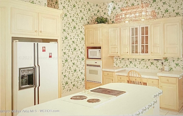 kitchen with light tile patterned floors, white appliances, and cream cabinetry