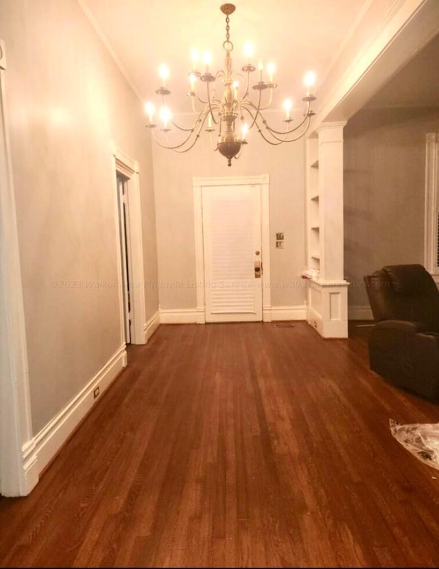 entryway featuring decorative columns, a chandelier, dark wood-type flooring, and ornamental molding