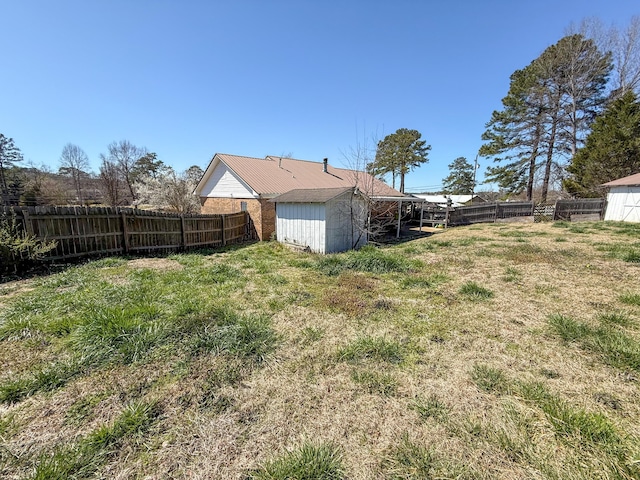 view of yard featuring a storage unit, an outbuilding, and a fenced backyard