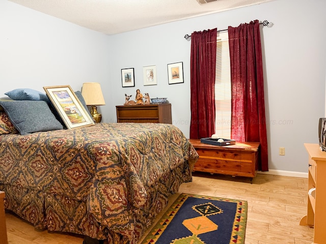 bedroom with light wood-type flooring, baseboards, and visible vents