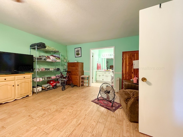 interior space featuring light wood-type flooring, a textured ceiling, and radiator heating unit