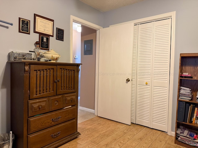 bedroom with light wood-style flooring, baseboards, a closet, and a textured ceiling