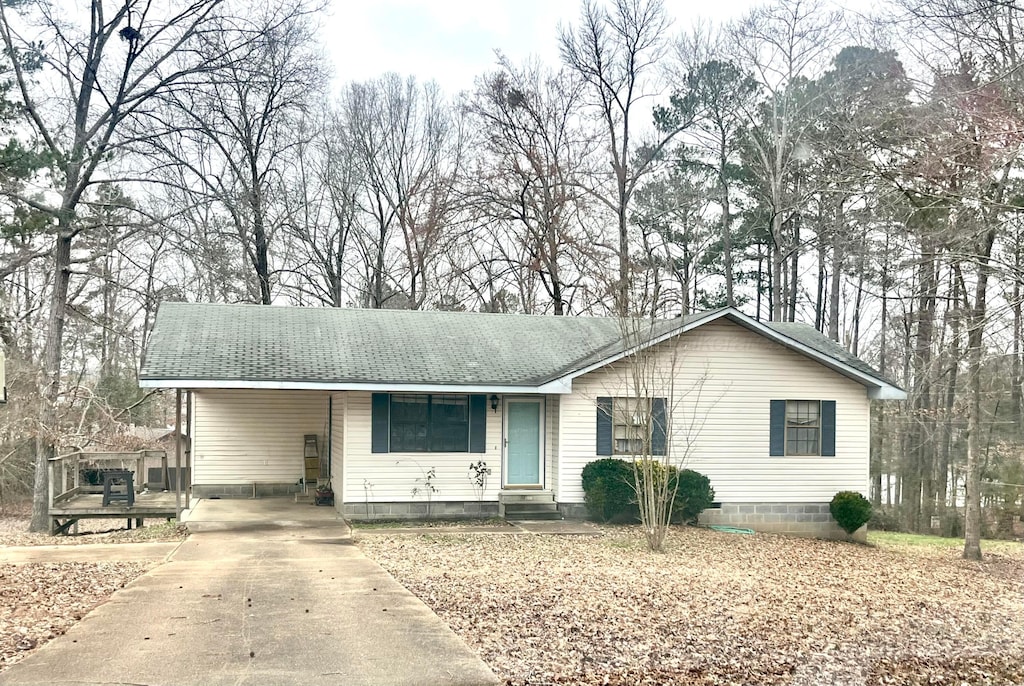 ranch-style home featuring entry steps, driveway, an attached carport, and roof with shingles