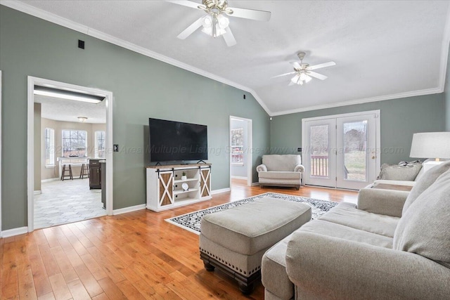 living room with crown molding, ceiling fan, hardwood / wood-style floors, vaulted ceiling, and french doors