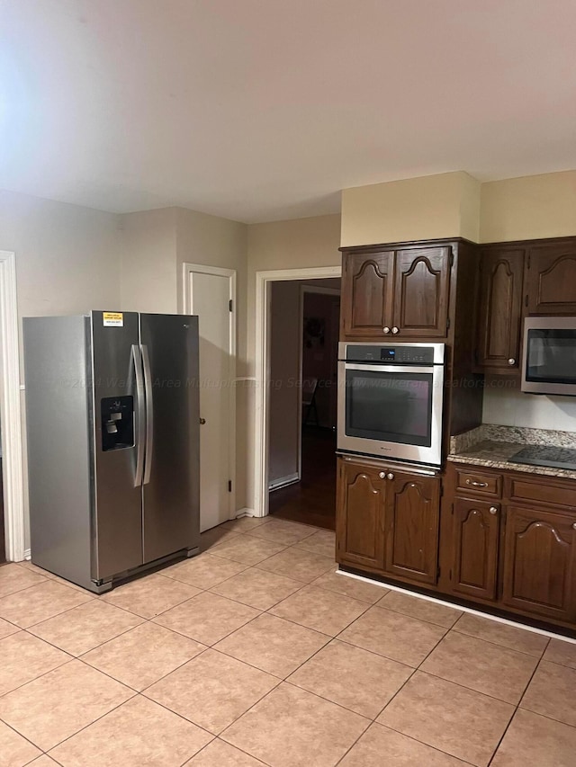 kitchen featuring appliances with stainless steel finishes, dark brown cabinetry, and light tile patterned flooring