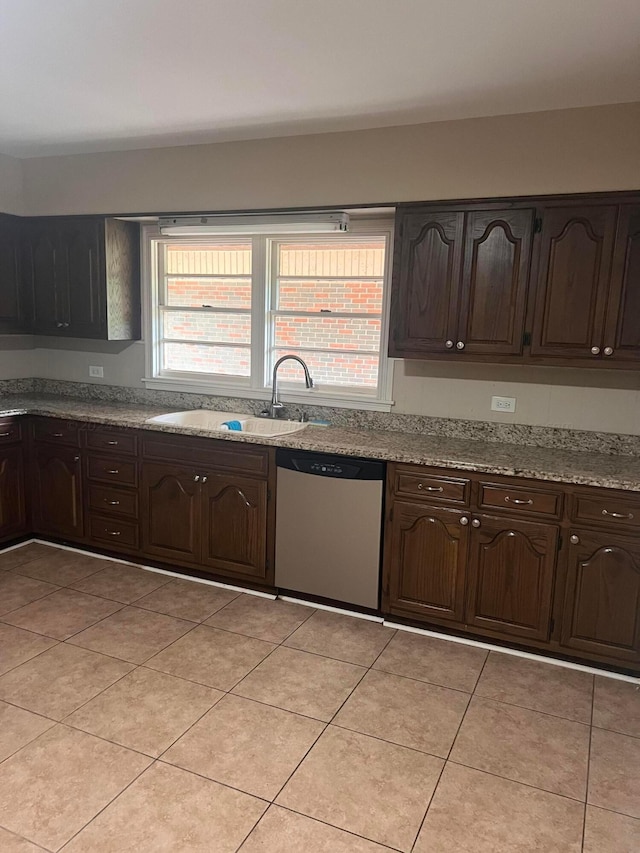 kitchen featuring dark brown cabinetry, dishwasher, light tile patterned flooring, and sink