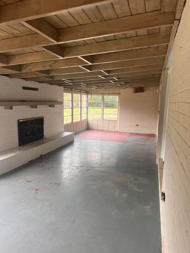 unfurnished living room with concrete flooring, a brick fireplace, and brick wall