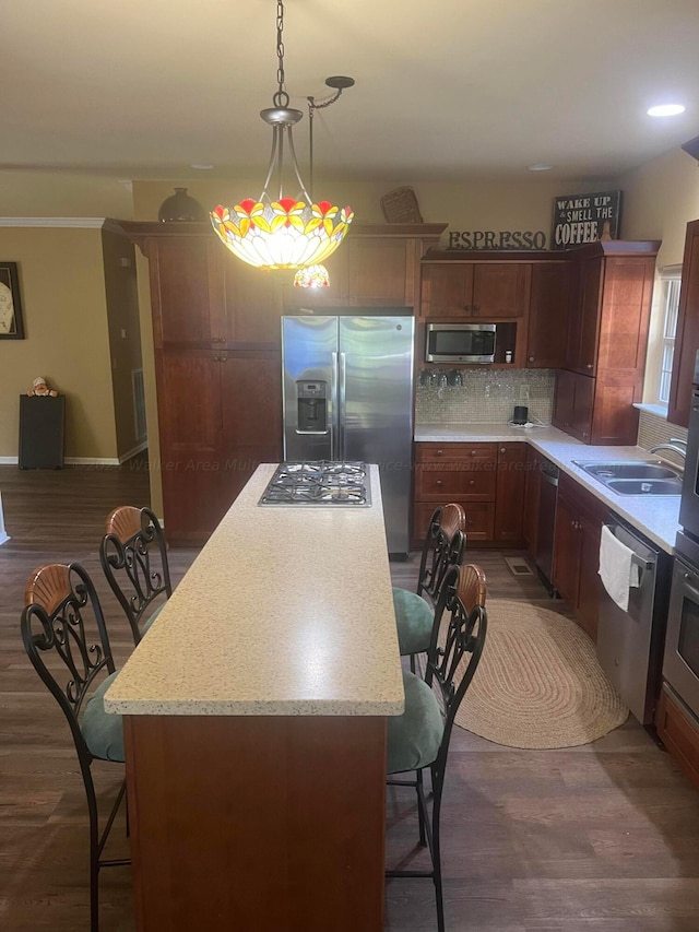 kitchen with sink, dark hardwood / wood-style floors, decorative light fixtures, a kitchen island, and appliances with stainless steel finishes